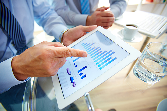 Modern people doing business, graphs and charts being demonstrated on the screen of a touchpad