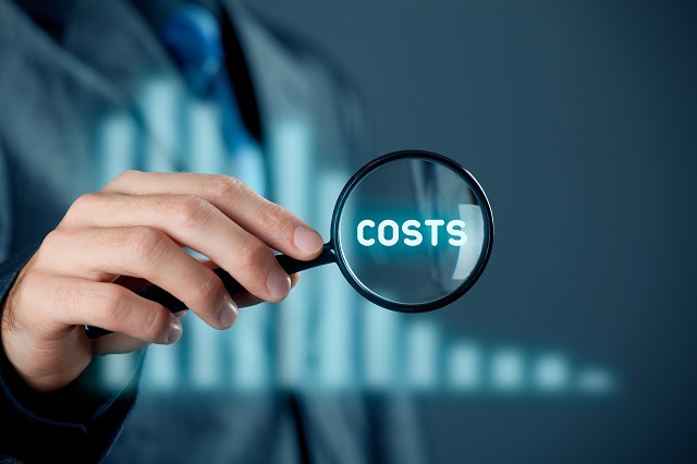 Focus on decrease (cut) costs concept. Businessman with magnifying glass enlarge word costs. Graph with decreasing costs on background.