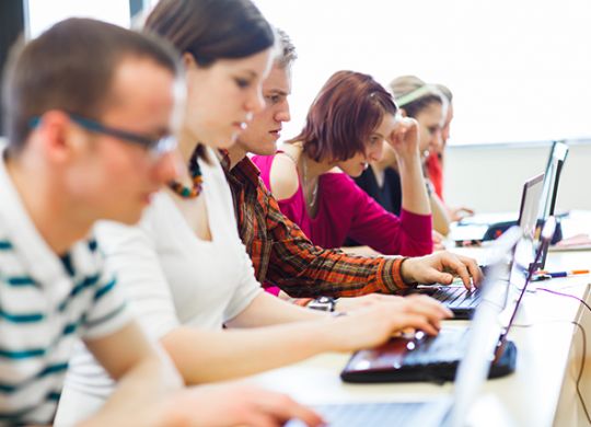 College students sitting in a classroom, using laptop computers during class (shallow DOF)